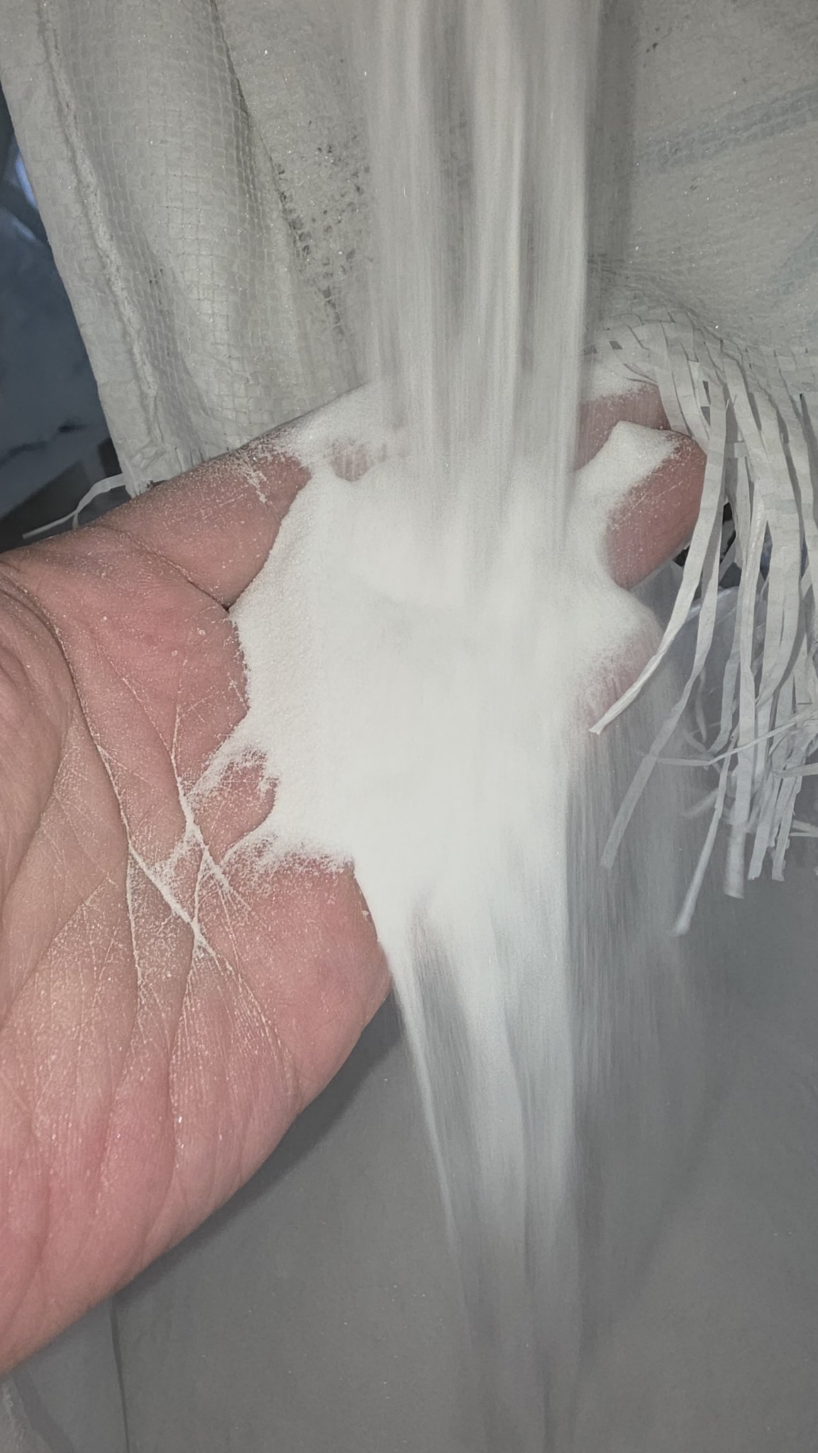 Fine white fused alumina grit pouring through fingers
